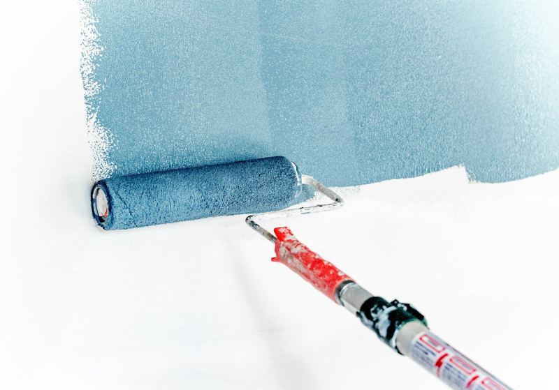 Paint roller applying colour to a wall