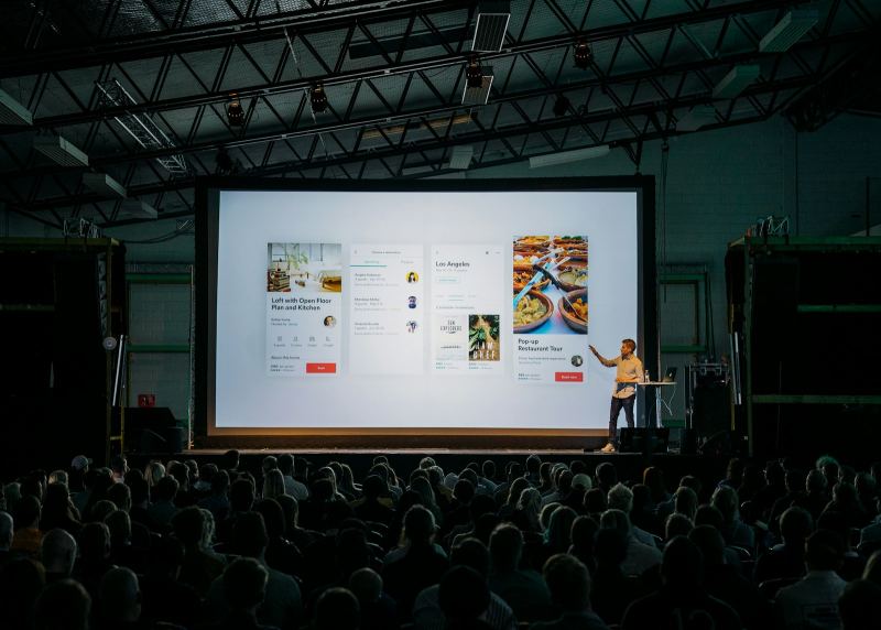 Presenter on stage in front of a large display screen